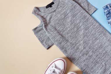 Moda kavramı. Kadın kentsel tarzı. Gri elbise ve yumuşak mavi arka plan üzerinde bej beyaz spor ayakkabı