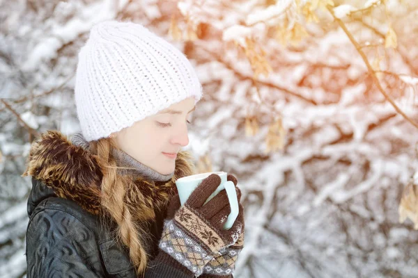 Chica en un sombrero blanco en invierno con taza de té, vista lateral, primer plano —  Fotos de Stock