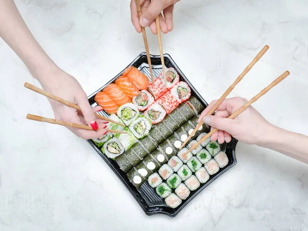 Yemek çubukları ve sushi seti ile üç el. Üstten Görünüm
