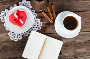 Defter bir kalem, bir kahve ile kalp kurabiye şeklinde.