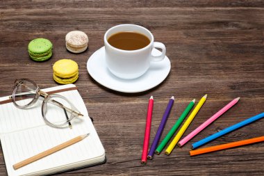 Kahve kupa, bademli kurabiye, renkli kalemler ve dizüstü