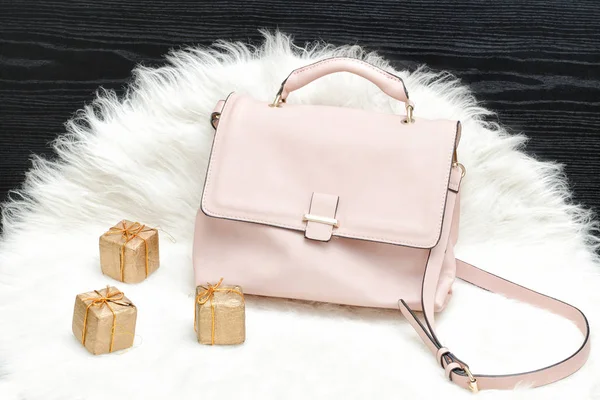 Pink bag and gift box on white fur, black table