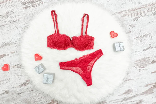 Burgundy lingerie set on white fur. Silver gift boxes and red candles — Stock Photo, Image