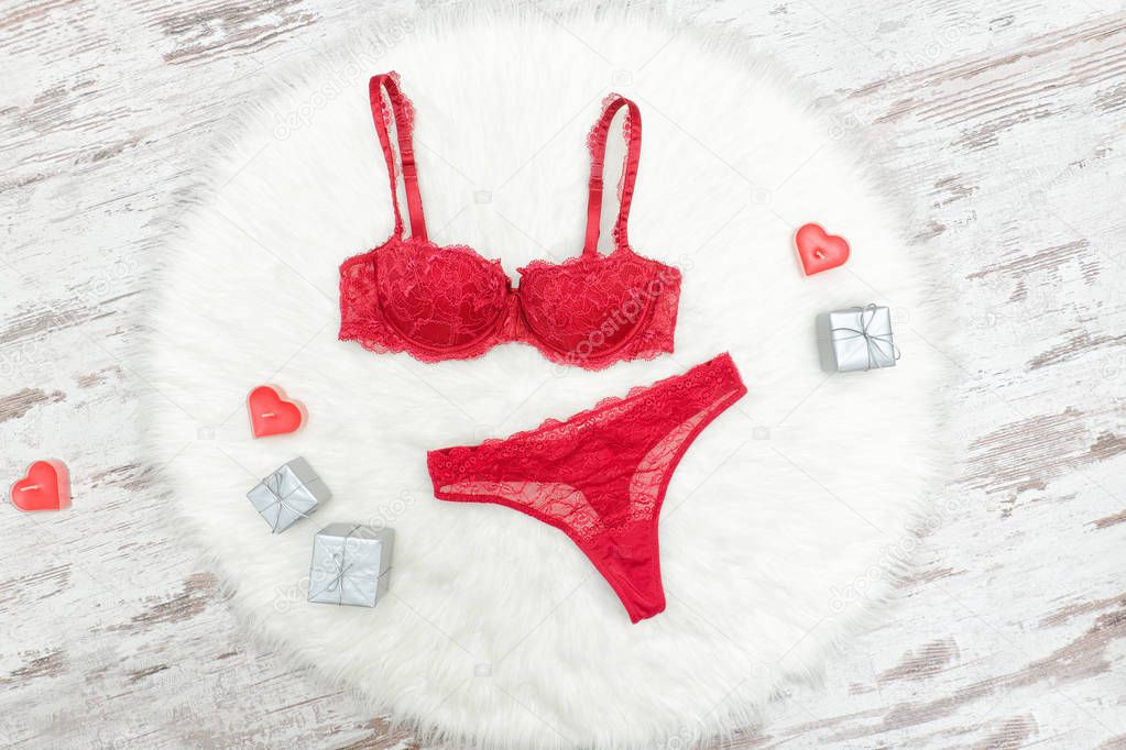 Burgundy lingerie set on white fur. Silver gift boxes and red candles