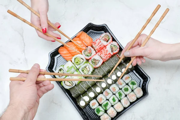 Yemek çubukları ve sushi seti ile üç el. Üstten Görünüm