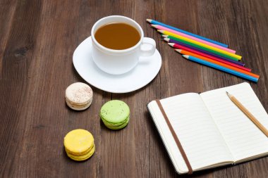 Kahve kupa, bademli kurabiye, renkli kalemler ve dizüstü