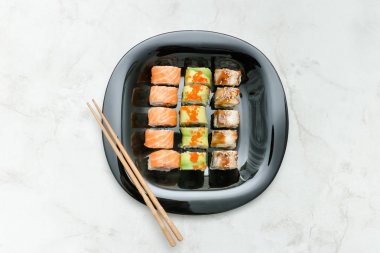 Siyah plaka ile çeşitli rulo ve yemek çubukları. Üstten Görünüm