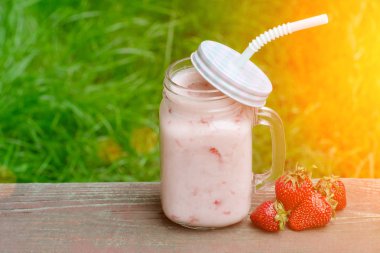 Yoğurt ve çilek yeşil çim bir arka plan üzerine bir fincan