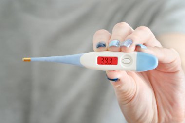 Elektronik termometre içinde bir el. Yüksek vücut sıcaklığı