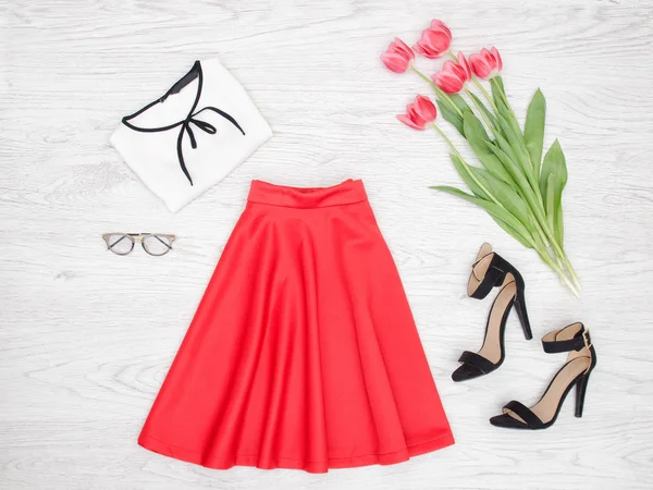 Fashion concept. Rode rok, blouse, bril, zwarte schoenen en roze tulpen. Bovenaanzicht — Stockfoto