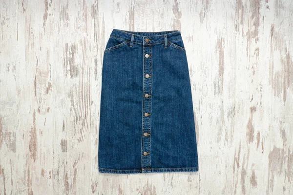 Blue denim skirt. Wooden background, fashionable concept