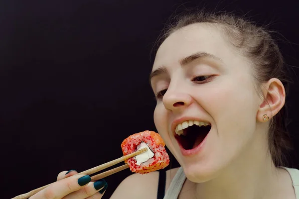 Kobieta zjada bułki z pałeczkami. Otwarte usta. Czarne tło — Zdjęcie stockowe