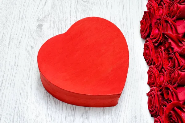 Hafif ahşap bir masa üzerinde bir kalp şeklinde ve bir buket gül kutusu — Stok fotoğraf
