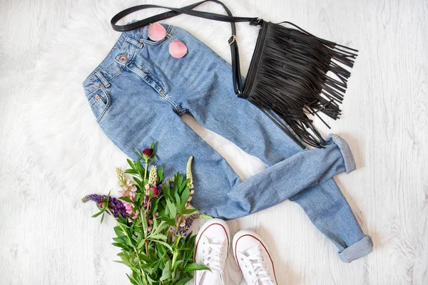 Pantalones vaqueros azules, bolso negro, zapatillas blancas y flores . — Foto de Stock