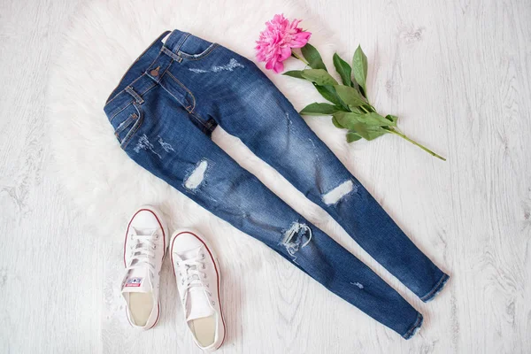 Jeans stracciati, sneakers bianche e peonia rosa. Fondo bianco — Foto Stock