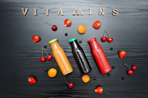 Three bottles with juice, fruit and inscription Vitamins