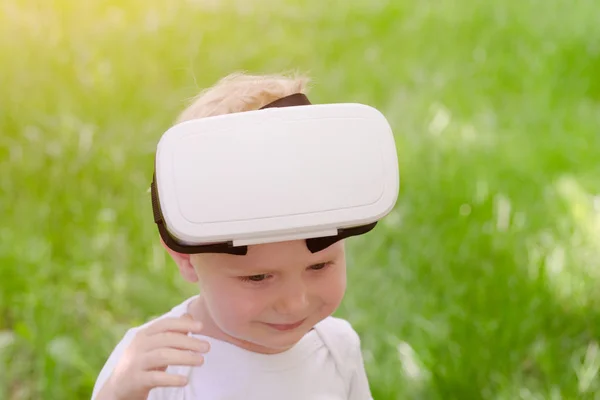 Мальчик снял свой шлем виртуальной реальности. Зеленая трава — стоковое фото