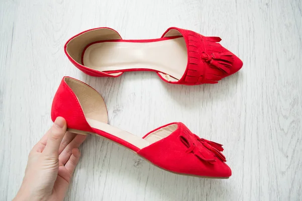 Sapatos abertos vermelhos na mão feminina. Fundo de madeira leve. Vista superior — Fotografia de Stock