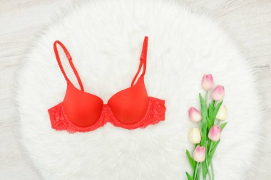 Moda kavramı. Beyaz kürk üzerinde kırmızı büstiyer. Lale buketi