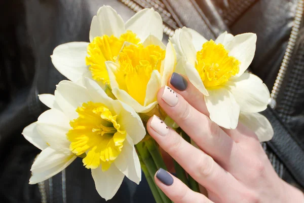 Mains féminines avec jonquilles, manucure. Gros plan — Photo