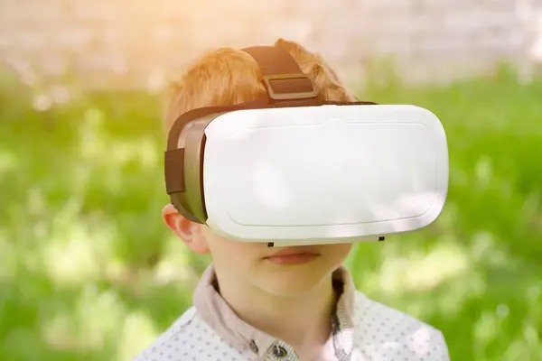 Хлопчик у шоломі віртуальної реальності на фоні зеленої трави — стокове фото