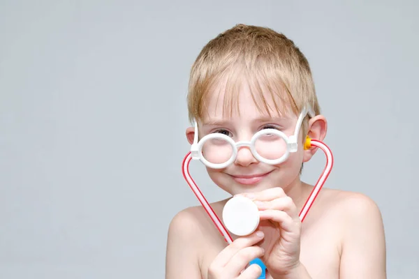 Rapaz bonito com óculos e fonendoscópio jogando médico. Retrato — Fotografia de Stock