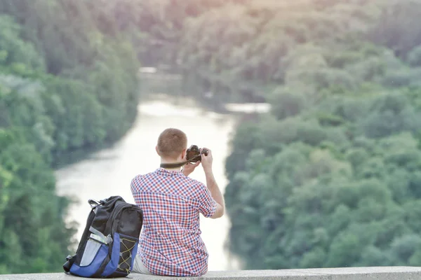 Člověk bere obrázky z kopce. Les a řeka pod — Stock fotografie