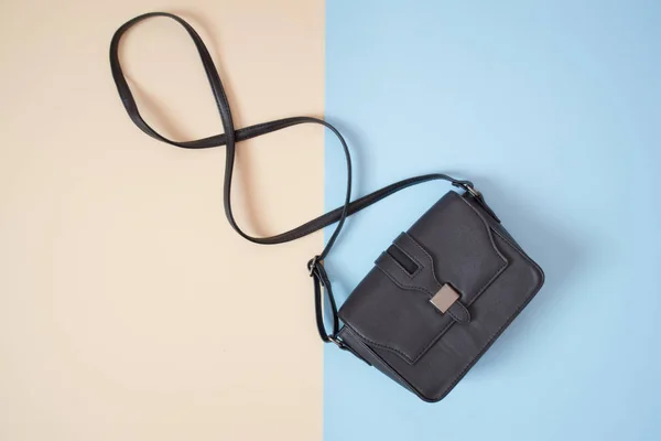 Concetto alla moda. Borsa nera. Tenero sfondo beige e blu — Foto Stock