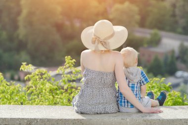 Anne ve oğlu yeşil orman ve köy uzakta arka plan üzerinde oturan