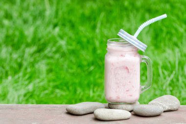 Bir fincan yoğurt çakıl taşı üzerinde. Yeşil çim arka plan. Metin için yer