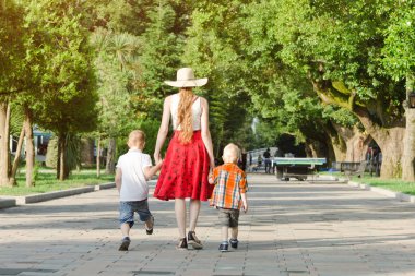 Anne ve iki oğlu parkta yürüyüş güneşli bir gün. Arkadan görüntülemek