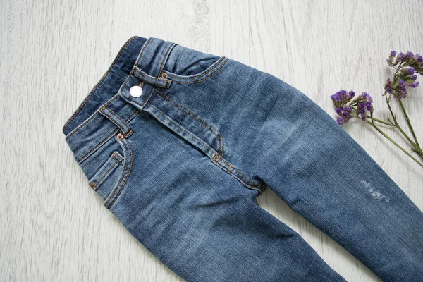 Jeans bleus et fleurs. Fond en bois. Concept tendance — Photo