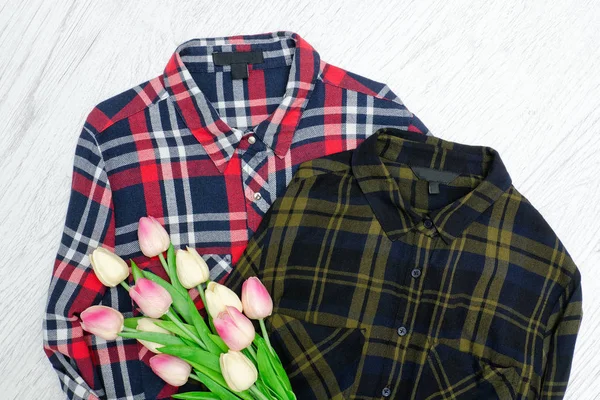 Módní pojem. Dvě kostkované košile a růžové tulipány. Dřevěné pozadí — Stock fotografie