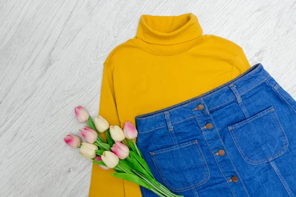 Concepto de moda. Cuello alto amarillo, falda azul y tulipanes rosados . — Foto de Stock