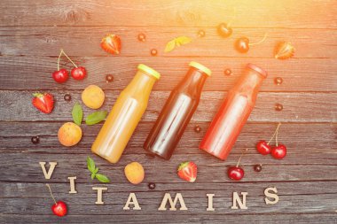 Üç şişe suyu, meyve ve yazıt vitamin. Ahşap arka plan