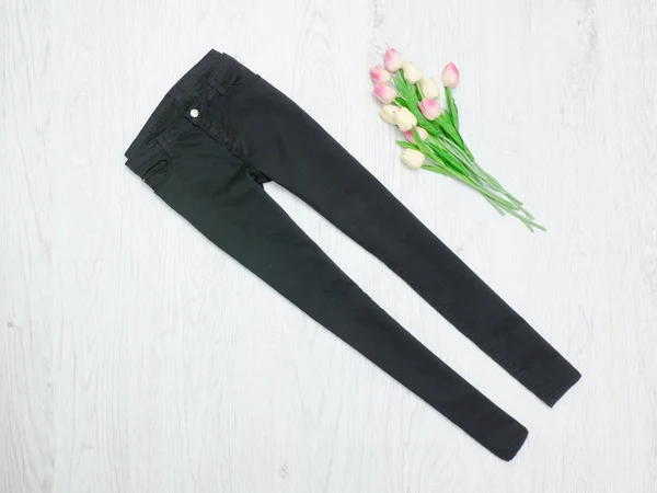 Concept de mode. Jeans noirs et tulipes roses. Fond bois — Photo