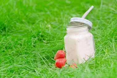 Yoğurt ve çilek yeşil çim bir arka plan üzerine bir fincan.