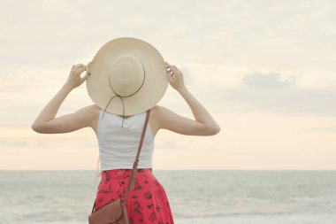 Şapkalı kız ayakta deniz, gün batımı. Arkadan Görünüm