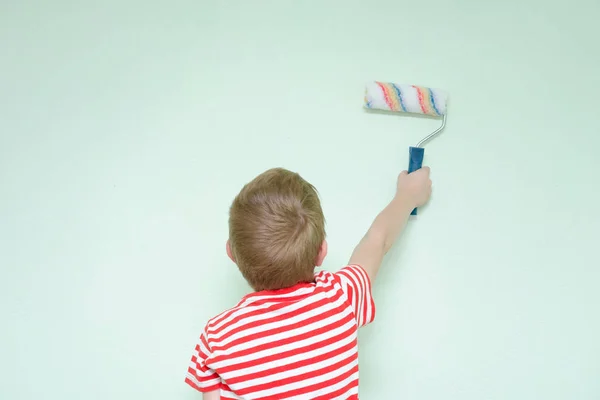 Boy paints the wall roller for painting. Back view — Stock Photo, Image