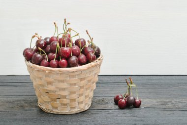 Kiraz ahşap bir masa üstünde sepetle. Kopya alanı