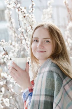 Bir fincan çay ayakta pencere ve gülümseme kızla. Şu yeni gelişen ağaç arka planda