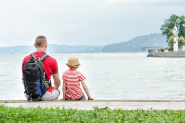 Baba ve oğul iskelede oturuyordu. Deniz, deniz feneri ve dağlar