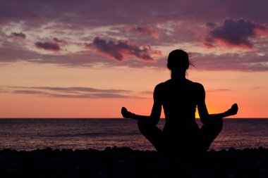 Lotus pozisyonu Sahilde meditasyon kadın. Siluet, gün batımı