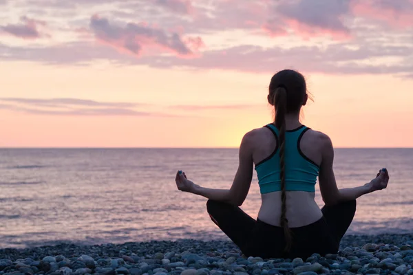 Vrouw mediteren op het strand in de lotuspositie. Zonsondergang. Achteraanzicht — Stockfoto