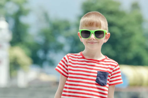 Chłopiec w T-shirt w paski i okulary Stojaki na tle morza. Portret — Zdjęcie stockowe