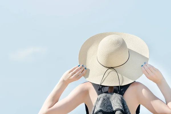 Menina em um chapéu em um contexto do céu claro. Visão traseira — Fotografia de Stock