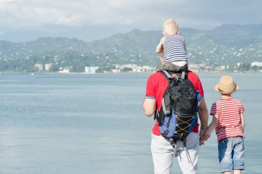 Babası iki oğlu ile sahilde hazır. Arkadan görüntülemek