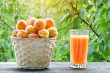 Bir hasır sepet ve yeşil bir arka plan üzerine suyu bir bardak kayısı