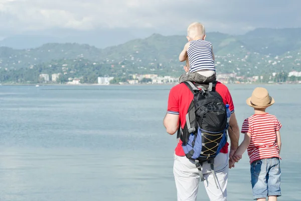 Babası iki oğlu ile sahilde hazır. Arkadan görüntülemek