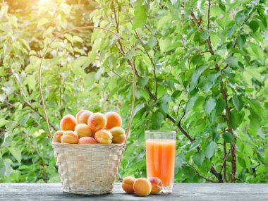 Bir hasır sepet ve yeşil bir arka plan üzerine suyu bir bardak kayısı